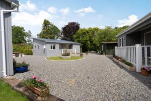 a gravel driveway with a white fence and a house at Ramsey Lodge Bier Wood Lodges in Tenby