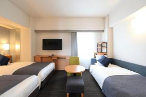 岡山市にあるホテルマイステイズ岡山のベッド2台とテレビが備わるホテルルームです。