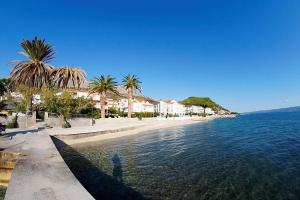 a beach with palm trees and houses and the water at Apartments with WiFi Podstrana, Split - 15970 in Podstrana