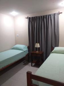 a bedroom with two beds and a table with a lamp at Tucuman Centro Departamento in San Miguel de Tucumán
