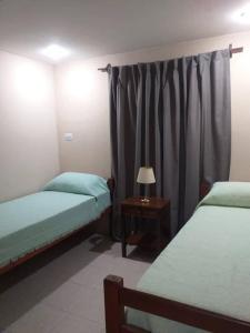 ein Schlafzimmer mit 2 Betten und einem Tisch mit einer Lampe in der Unterkunft Tucuman Centro Departamento in San Miguel de Tucumán