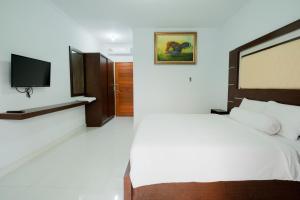 Kadek Bagus Guesthouse Denpasar Mitra RedDoorz في كيروبوكان: غرفة نوم بسرير وتلفزيون بشاشة مسطحة