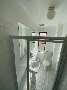 a white bathroom with a toilet and a sink at Normandie Wollongong in Wollongong
