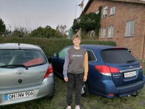 a young boy is standing between two cars at Thisted Øst Bed & No Breakfast in Thisted