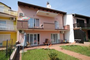 a house with a balcony and a yard with chairs at Apartments with a parking space Zambratija, Umag - 2533 in Savudrija