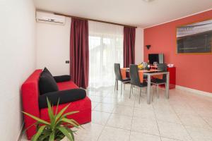 a living room with a red couch and a table at Apartments with a parking space Zambratija, Umag - 2533 in Savudrija