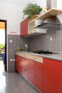 cocina con armarios rojos y encimera en Apartments by the sea Umag - 2528 en Umag