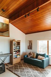 una sala de estar con sofá azul y techos de madera. en Redgate Homestead, en Hartley