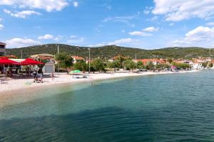 a beach with people sitting on the sand and the water at Apartments with a parking space Vinisce, Trogir - 2987 in Vinišće