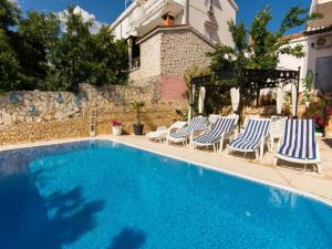 a swimming pool with lounge chairs and a house at Villa Stil in Trogir