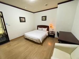 1 dormitorio con cama, escritorio y sofá en Abbo Hotel, en Tainan