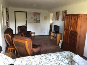 a bedroom with a bed and chairs and a dresser at Walsh Farm Farmstay in Milton