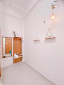 Habitación con pared blanca, espejo y estanterías. en Lantana Homestay, en Da Lat