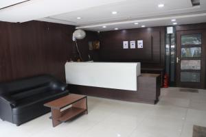 a lobby with a black leather chair and a table at Hotel Chandra in Jamshedpur