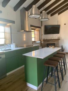 a kitchen with green cabinets and a large island with stools at PiluPeta Casa de Aldea 