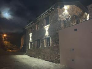 ein Steingebäude mit seitlicher Beleuchtung in der Nacht in der Unterkunft PiluPeta Casa de Aldea 