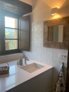 a white bathroom with a sink and a window at PiluPeta Casa de Aldea 