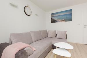 a living room with a couch and a clock on the wall at Two-Bedroom Apartament Gdansk 650 m Brzeźno Beach by Noclegi Renters in Gdańsk +20 photos
