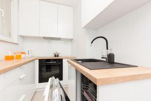 a kitchen with white cabinets and a black sink at Two-Bedroom Apartament Gdansk 650 m Brzeźno Beach by Noclegi Renters in Gdańsk