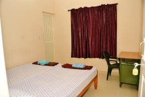 a bedroom with two beds and a desk and a window at Sheeba's Homestay in Cochin