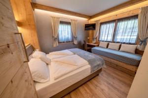 um quarto com uma cama, um sofá e janelas em Hotel Siera Hof em Sappada
