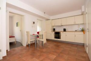 a kitchen with white cabinets and a table and chairs at Ferienwohnung am Sandbarg in Jesteburg