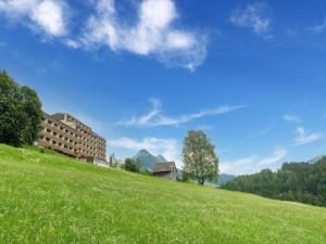 a grassy hill with a building on top of it at Apartment in Tauplitz with sauna and pool in Tauplitz