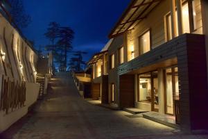 Hotel Royale Retreat - Luxury Hotel In Shimla في شيملا: شارع فارغ بالليل بجوار مباني