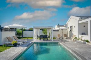 - une piscine avec des chaises et des parasols à côté d'une maison dans l'établissement Blue Wind Villa II, à Sarakinádhon