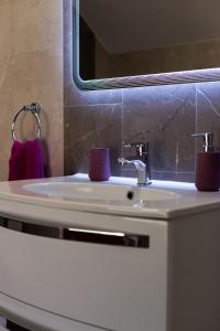 La salle de bains est pourvue d'un lavabo avec des tasses violettes. dans l'établissement Apartments River, à Otočac