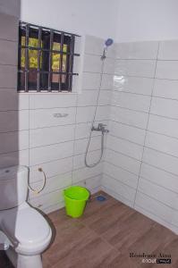 a bathroom with a toilet and a green bucket at RESIDENCE AINA in Abomey-Calavi