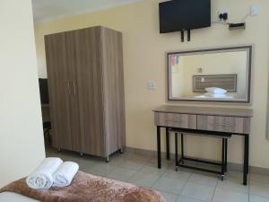 a bathroom with a dresser and a mirror and a bed at Mogale Royal Gardens in Polokwane