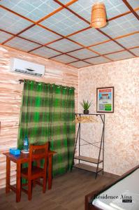 una habitación con una mesa y una cortina verde en RESIDENCE AINA, en Abomey-Calavi