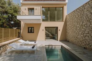 a house with a swimming pool and a brick wall at Paleros Bay Villas in Paleros