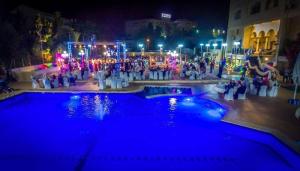 un grupo de personas de pie alrededor de una piscina por la noche en Casablanca Hotel Ramallah, en Ramallah