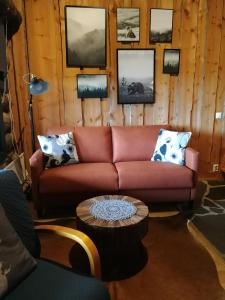 盧卡的住宿－Chill Cave - logwood cottage，客厅配有红色的沙发和墙上的照片
