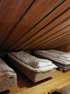 2 Betten in einem Zimmer mit Holzdecke in der Unterkunft Chill Cave - logwood cottage in Ruka