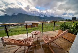 two chairs and a table on a deck with mountains at Kazbegi Glamping in Stepantsminda
