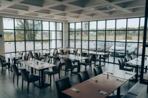 a dining room with tables and chairs and windows at Amigo Hotel Bintulu in Bintulu