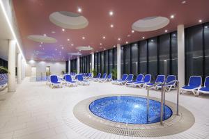 une grande chambre avec des chaises et une piscine dans l'établissement Apartment Aurora, à Moravske Toplice