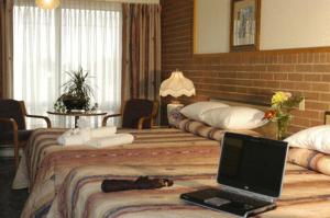 a hotel room with two beds with a laptop on the bed at Motel Du Chevalier in Gatineau