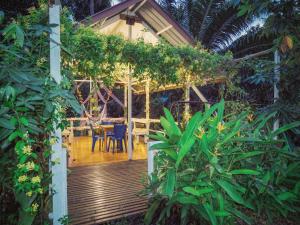 una casa con terrazza in legno con tavolo e sedie di Timba Garden FREE TOWN AND JETTY TRANSPORT a Semporna