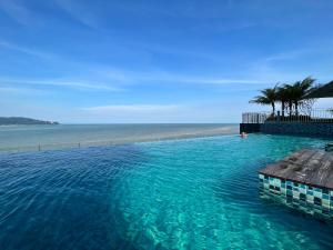 a swimming pool next to a beach with palm trees at IMPERIUM RESIDENCE KUANTAN [Seaview] Family Suite in Kuantan