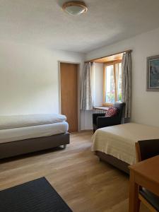 um quarto de hotel com duas camas e uma cadeira em Hotel Adler Garni em Zernez