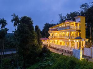 a large yellow house with lights on at The Hosteller Coorg, Madikeri in Madikeri