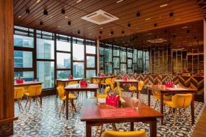 a restaurant with tables and yellow chairs and windows at Ginger Mumbai, Goregaon in Mumbai