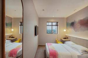 a hotel room with two beds and a mirror at Ginger Mumbai, Goregaon in Mumbai