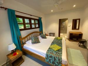 1 dormitorio con 1 cama grande y cortinas azules en Coin D'or en Anse Possession
