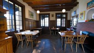 un restaurante con mesas y sillas de madera y ventanas en Leissigen Youth Hostel, en Leissigen
