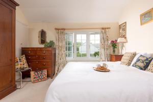 a bedroom with a large white bed and a window at Pump Cottage and Annexe, Gwithian in Gwithian